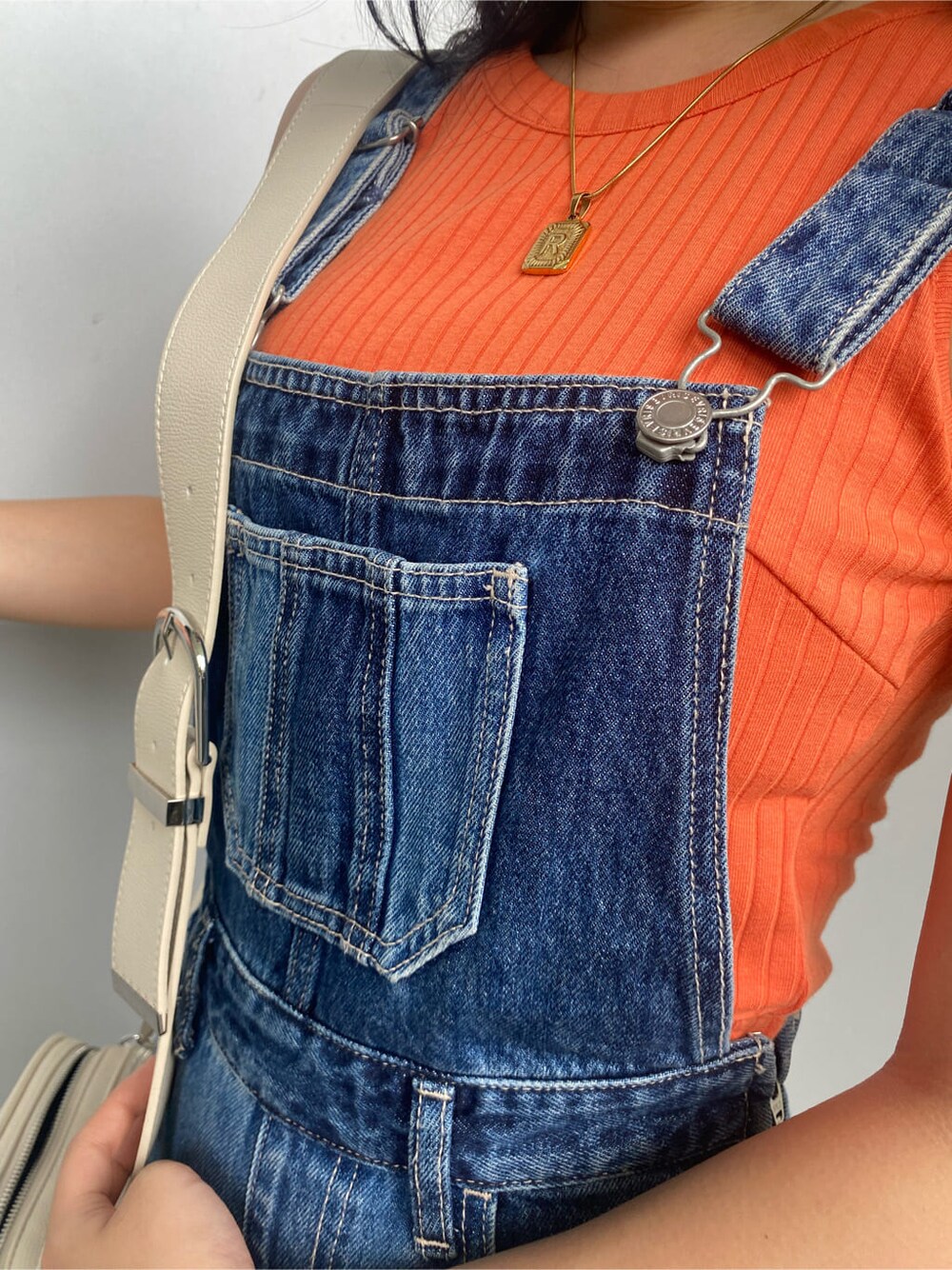 ホワイト系のショルダーバッグ、ブルー系のサロペット/オーバーオール、オレンジ系のタンクトップを着用したレディースの夏コーディネートの4枚目の写真