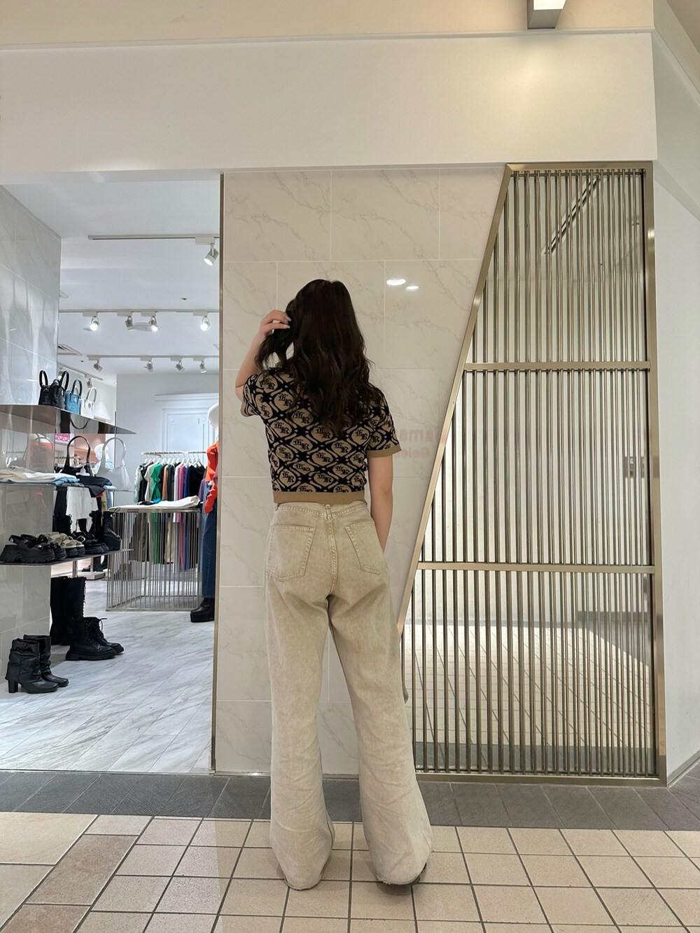 ベージュ系のニット/セーター、ベージュ系のデニムパンツ、ブラック系のブーツを着用したレディースの春コーディネートの3枚目の写真