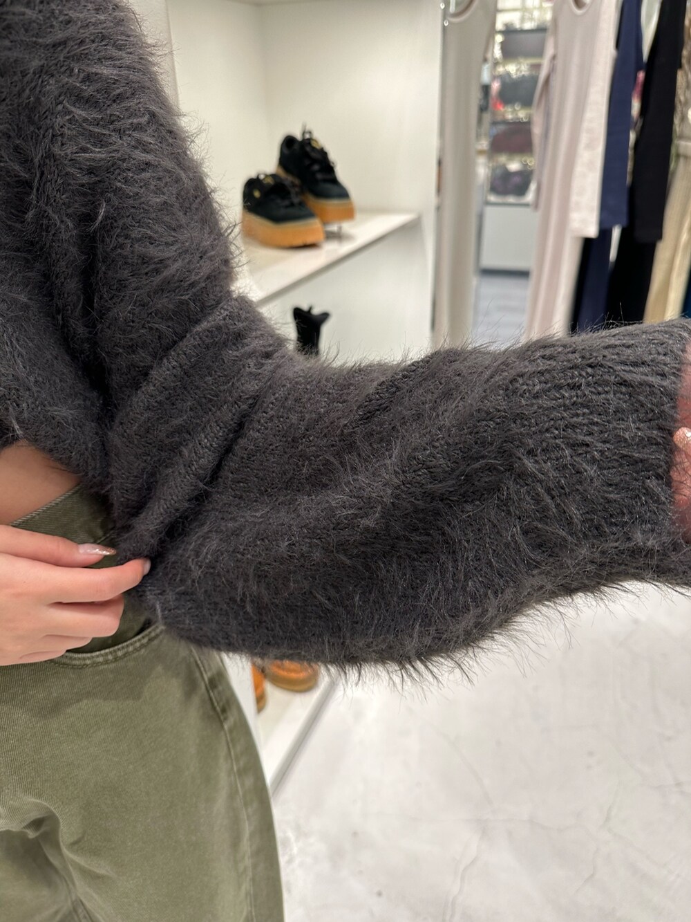 グリーン系のデニムパンツ、グレー系のニット/セーター、ブラック系のショルダーバッグを着用したレディースの冬コーディネートの6枚目の写真