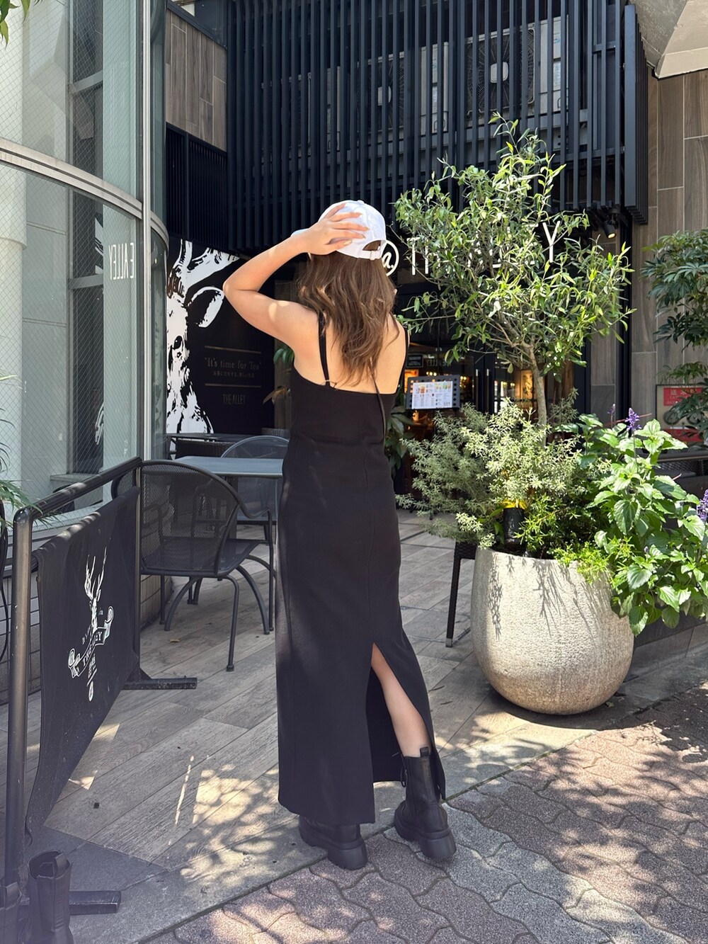 ブラック系のワンピース、ブラック系のブーツ、ホワイト系のキャップを着用したレディースの春コーディネートの3枚目の写真