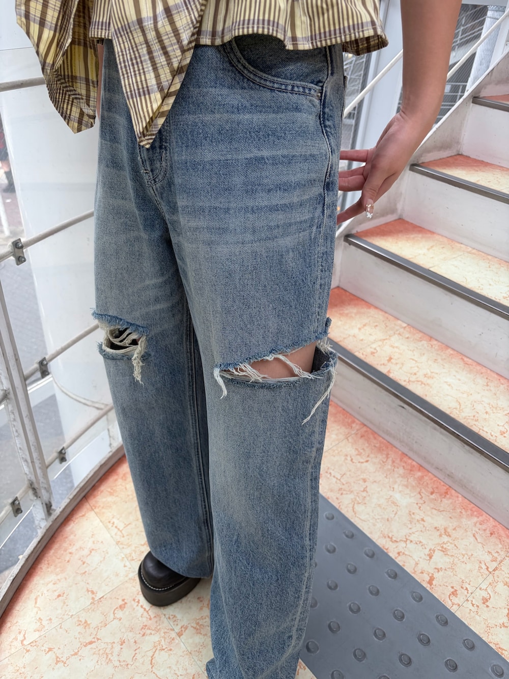 イエロー系のキャミソール、ブルー系のデニムパンツ、ブラック系のブーツを着用したレディースの夏コーディネートの7枚目の写真
