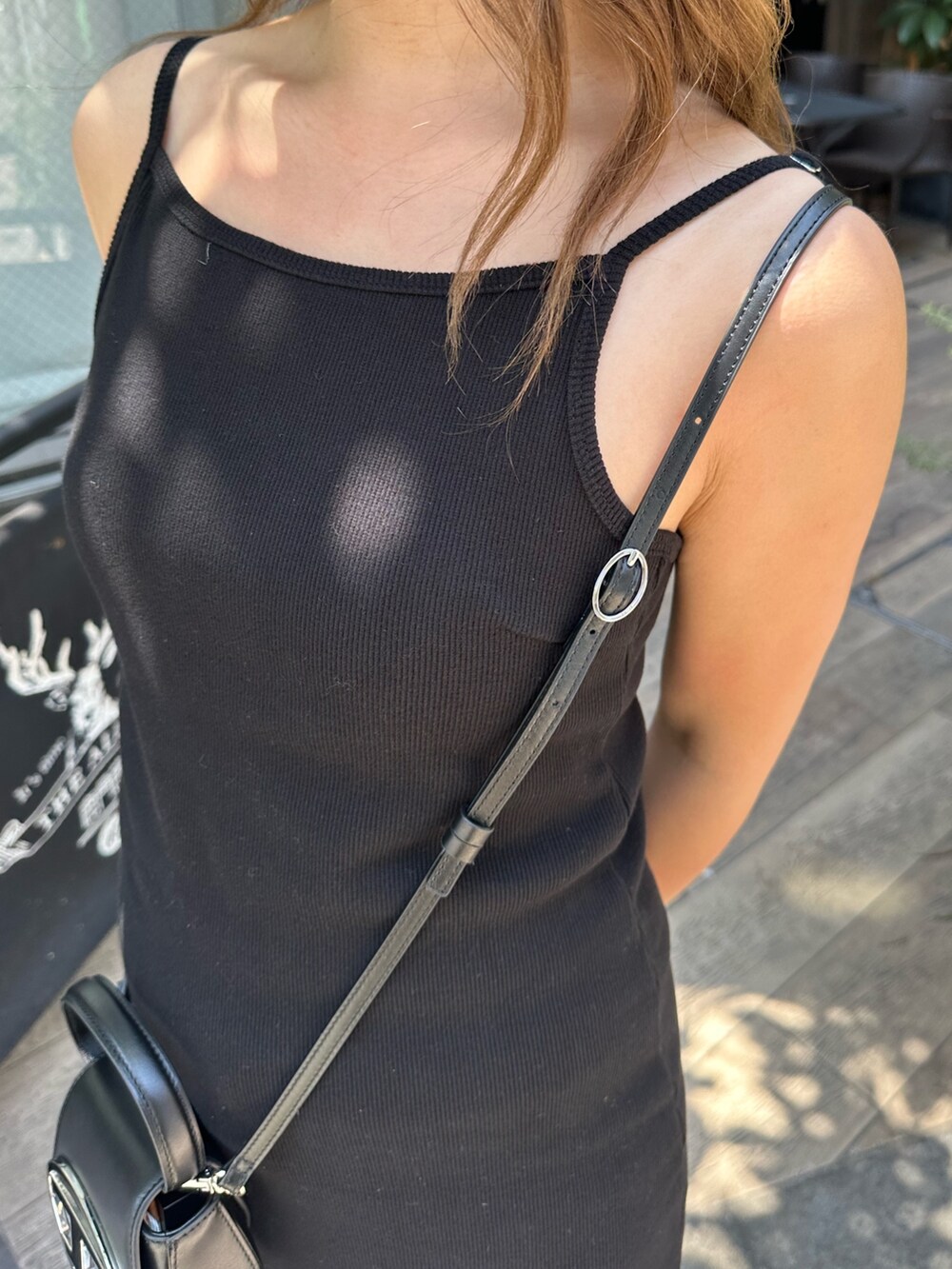 ブラック系のワンピース、ブラック系のブーツ、ホワイト系のキャップを着用したレディースの春コーディネートの6枚目の写真