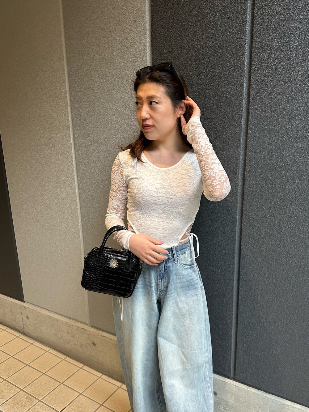 ブルー系のデニムパンツ、ホワイト系のTシャツ/カットソー、ブラック系のショルダーバッグを着用したレディースの春コーディネートの4枚目の写真