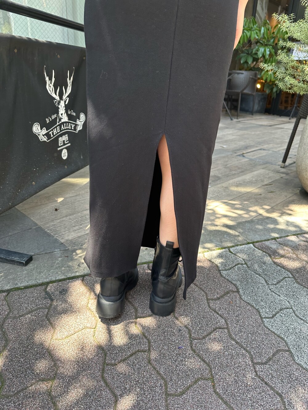 ブラック系のワンピース、ブラック系のブーツ、ホワイト系のキャップを着用したレディースの春コーディネートの8枚目の写真