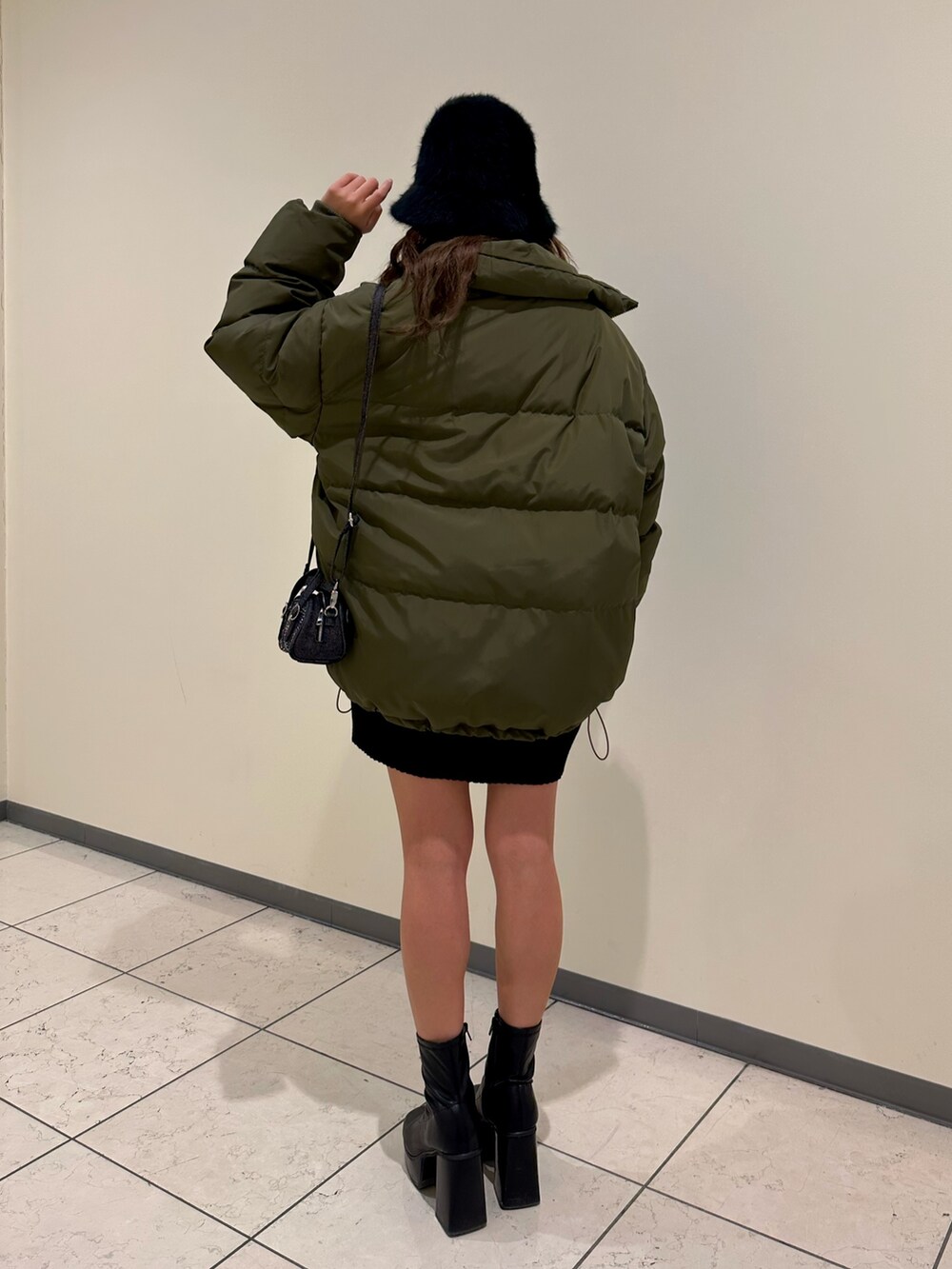 ブラック系のブーツ、ブラック系のニット/セーター、グリーン系のダウンジャケット/コートを着用したレディースの冬コーディネートの3枚目の写真