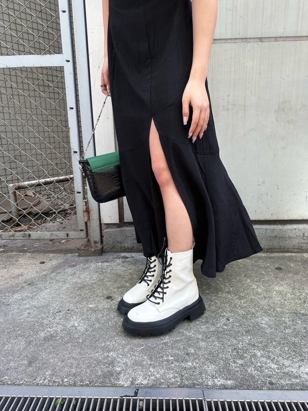 ブラック系のワンピース、ホワイト系のブーツ、ブラック系のショルダーバッグを着用したレディースの春コーディネートの6枚目の写真