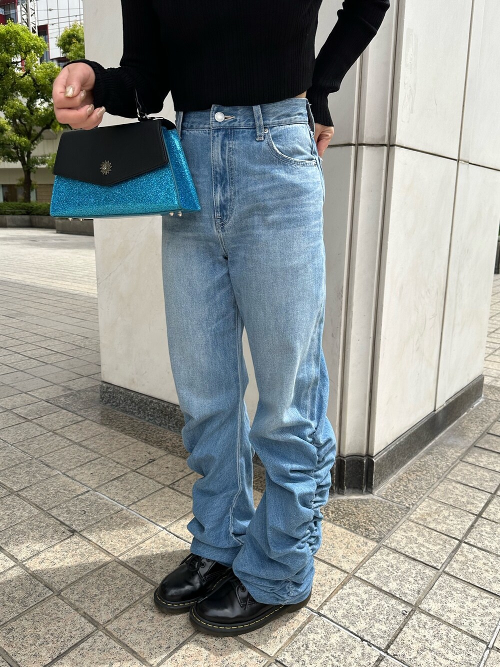 ブルー系のデニムパンツ、ブルー系のショルダーバッグ、ブラック系のニット/セーターを着用したレディースの春コーディネートの5枚目の写真