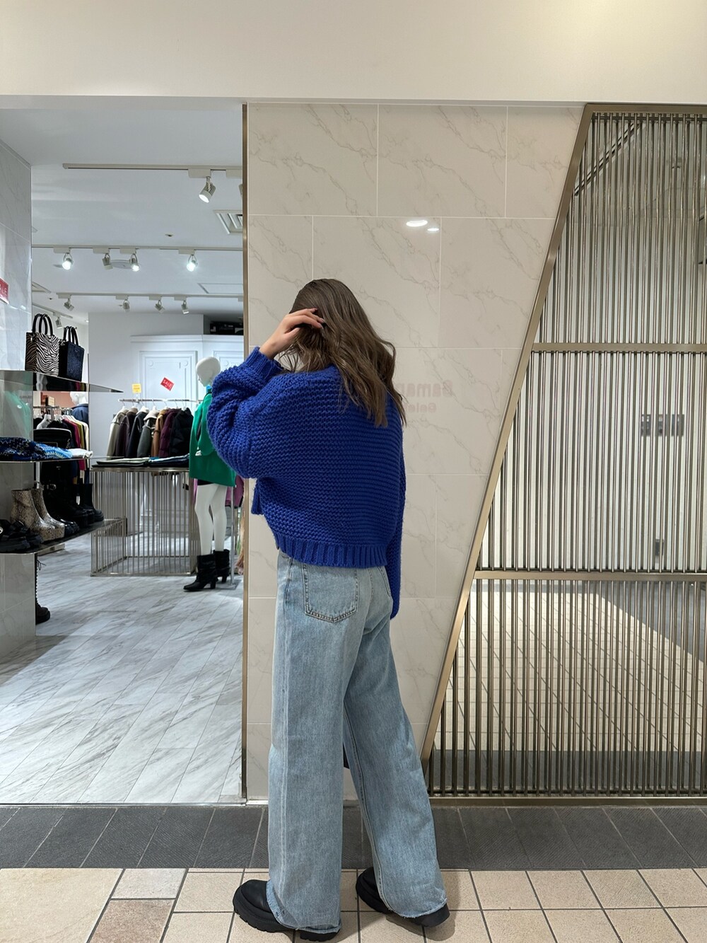 ブラック系のハンドバッグ、ブルー系のニット/セーター、ブルー系のデニムパンツを着用したレディースの冬コーディネートの2枚目の写真