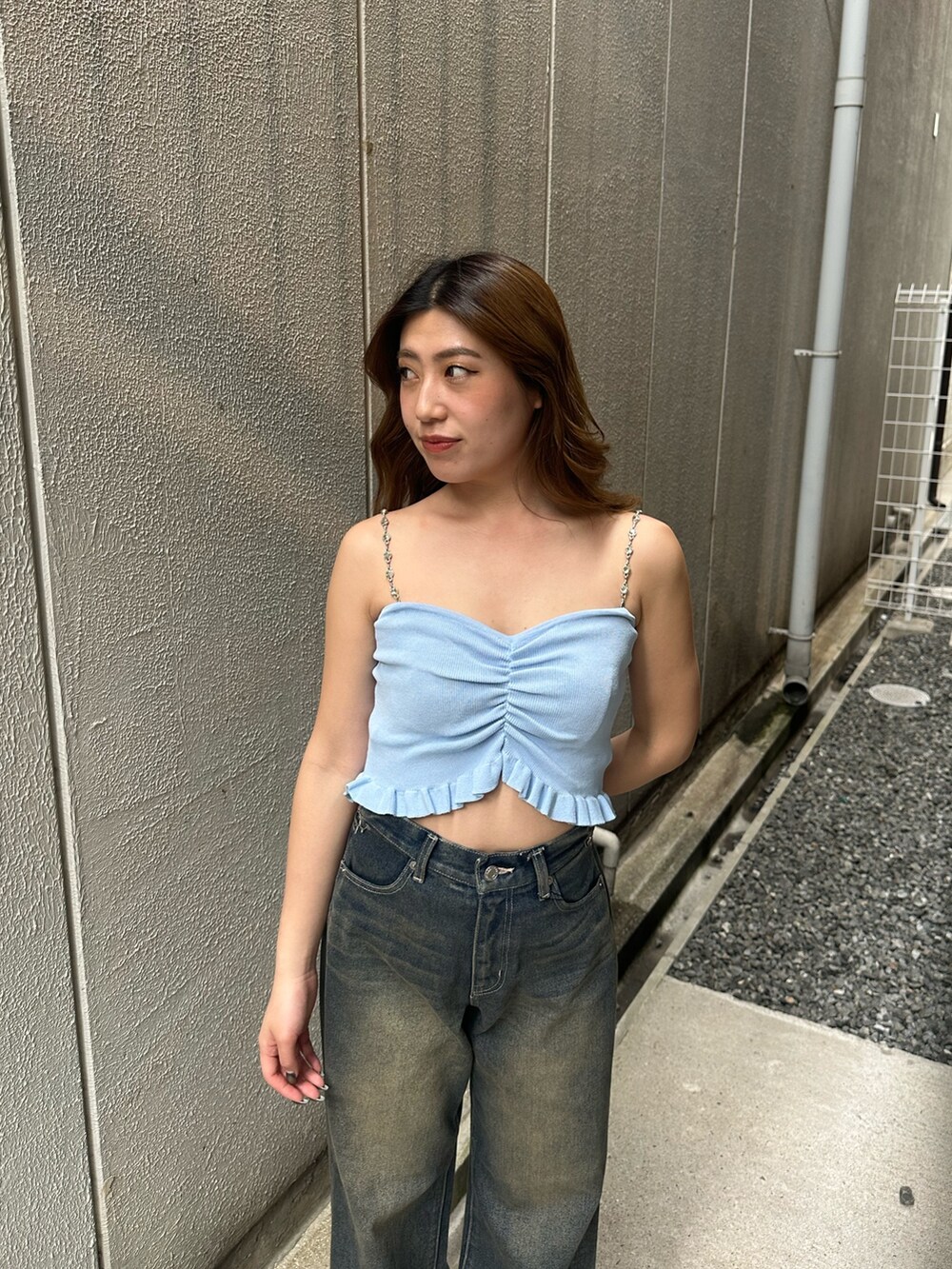 ブルー系のデニムパンツ、ブラック系のサンダル、ブルー系のキャミソールを着用したレディースの夏コーディネートの4枚目の写真