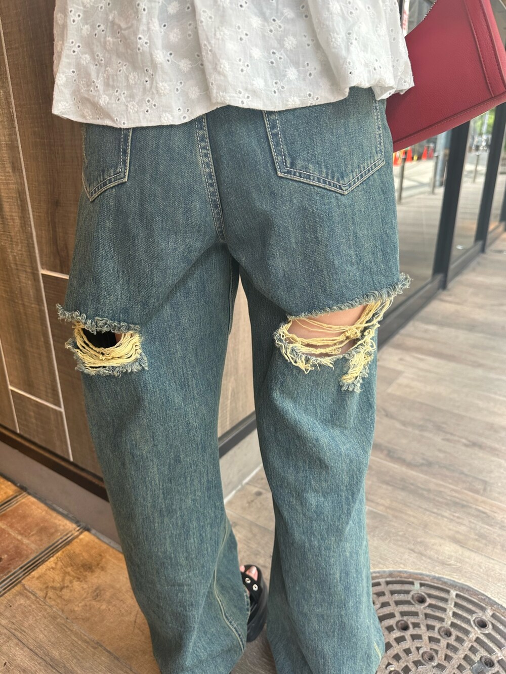 ブルー系のデニムパンツ、ホワイト系のシャツ/ブラウス、レッド系のショルダーバッグを着用したレディースの夏コーディネートの9枚目の写真