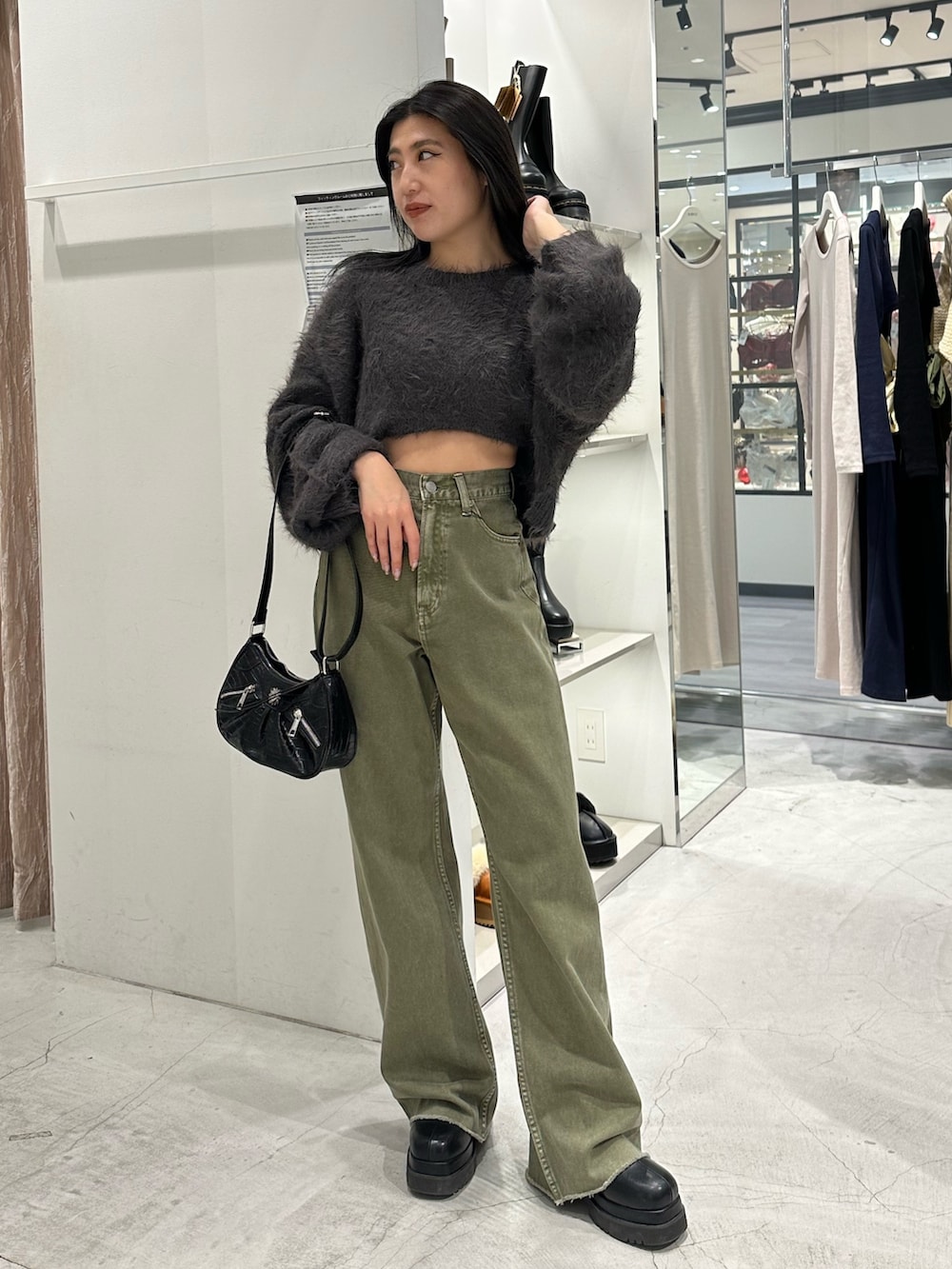 グリーン系のデニムパンツ、グレー系のニット/セーター、ブラック系のショルダーバッグを着用したレディースの冬コーディネートの3枚目の写真