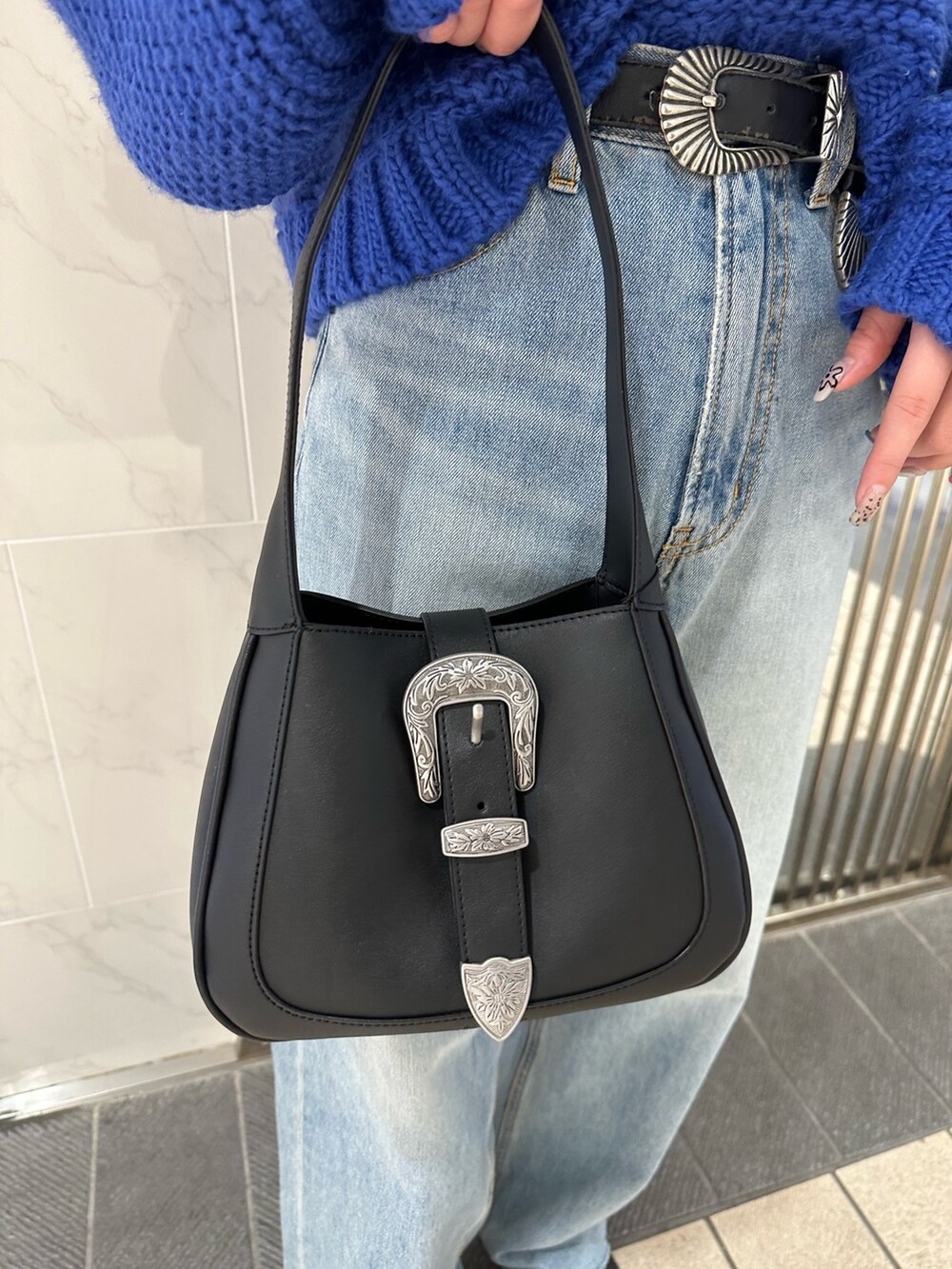 ブラック系のハンドバッグ、ブルー系のニット/セーター、ブルー系のデニムパンツを着用したレディースの冬コーディネートの6枚目の写真