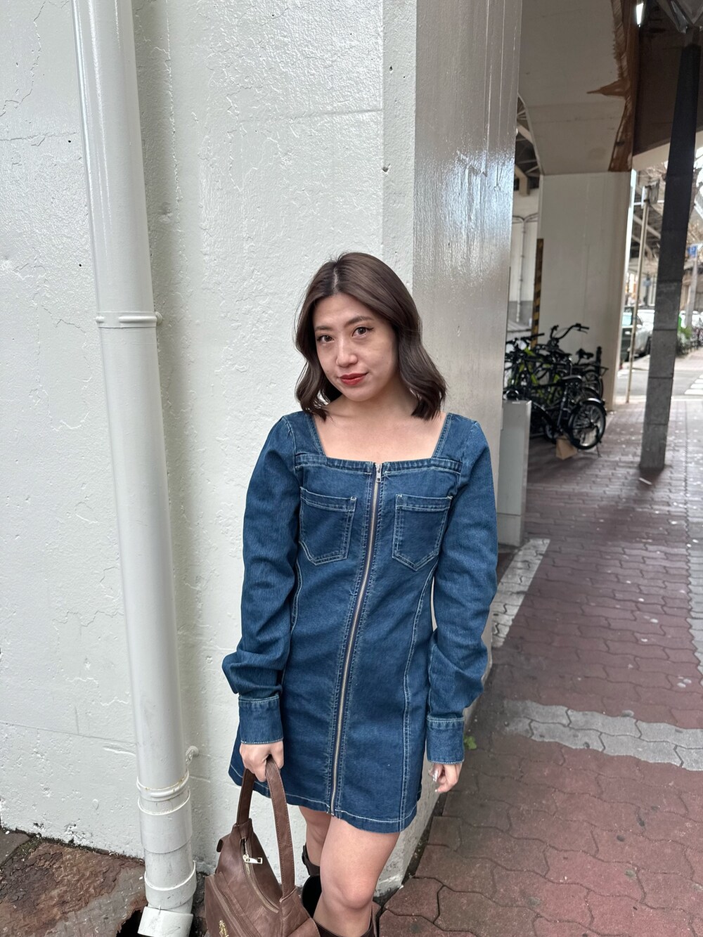 ブラウン系のブーツ、ブルー系のワンピース、ブラウン系のハンドバッグを着用したレディースの冬コーディネートの5枚目の写真