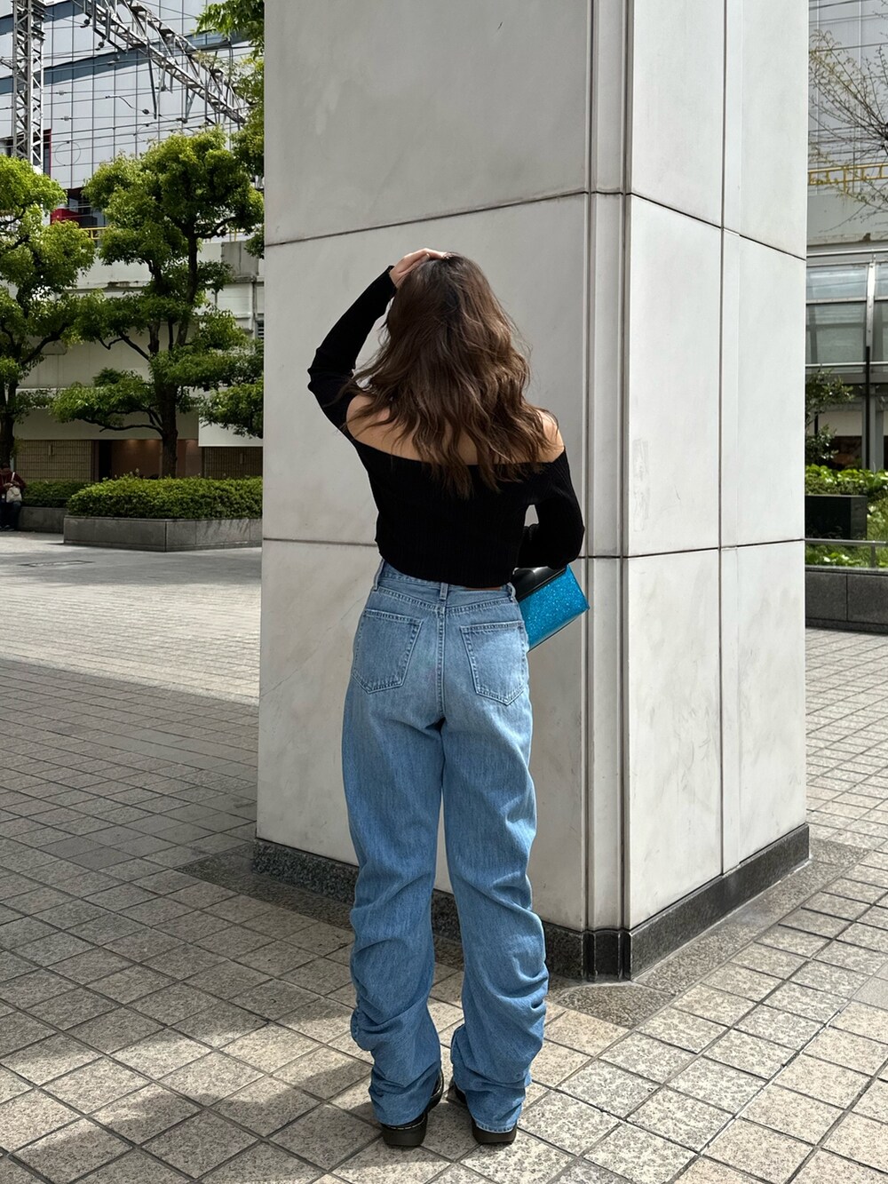 ブルー系のデニムパンツ、ブルー系のショルダーバッグ、ブラック系のニット/セーターを着用したレディースの春コーディネートの3枚目の写真