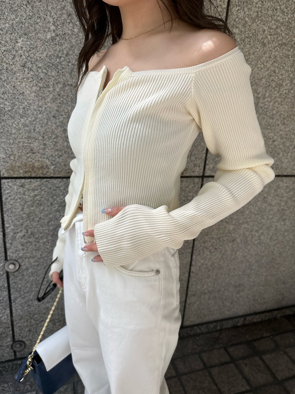 ホワイト系のニット/セーター、ホワイト系のデニムパンツ、ブルー系のショルダーバッグを着用したレディースの春コーディネートの5枚目の写真