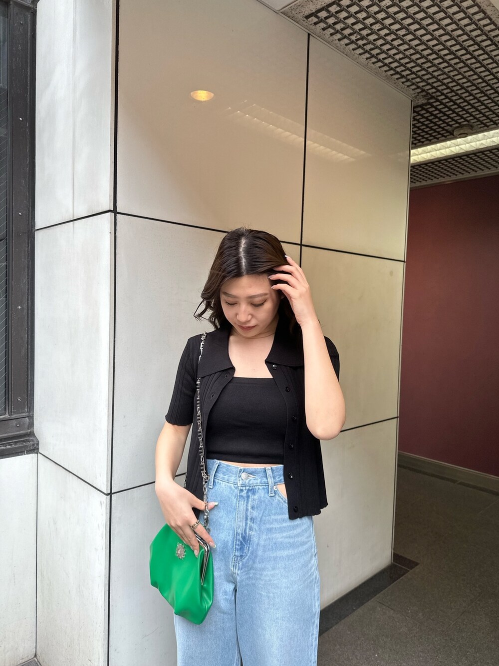 ブラック系のニット/セーター、ブルー系のデニムパンツ、グリーン系のショルダーバッグを着用したレディースの春コーディネートの3枚目の写真