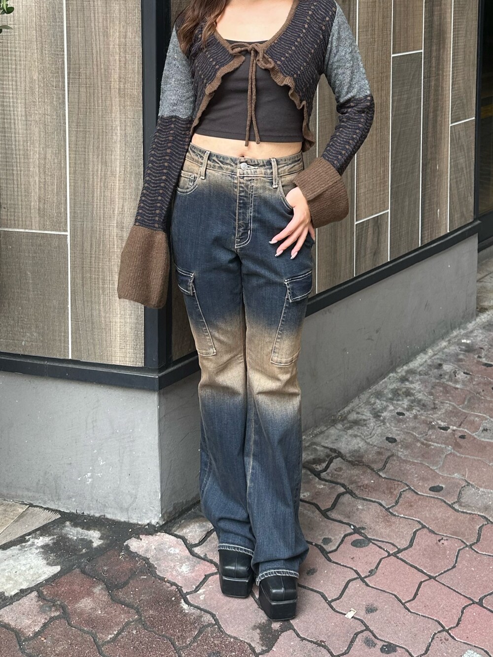 ブルー系のデニムパンツ、ブラック系のブーツ、ブラウン系のニット/セーターを着用したレディースの秋コーディネートの4枚目の写真