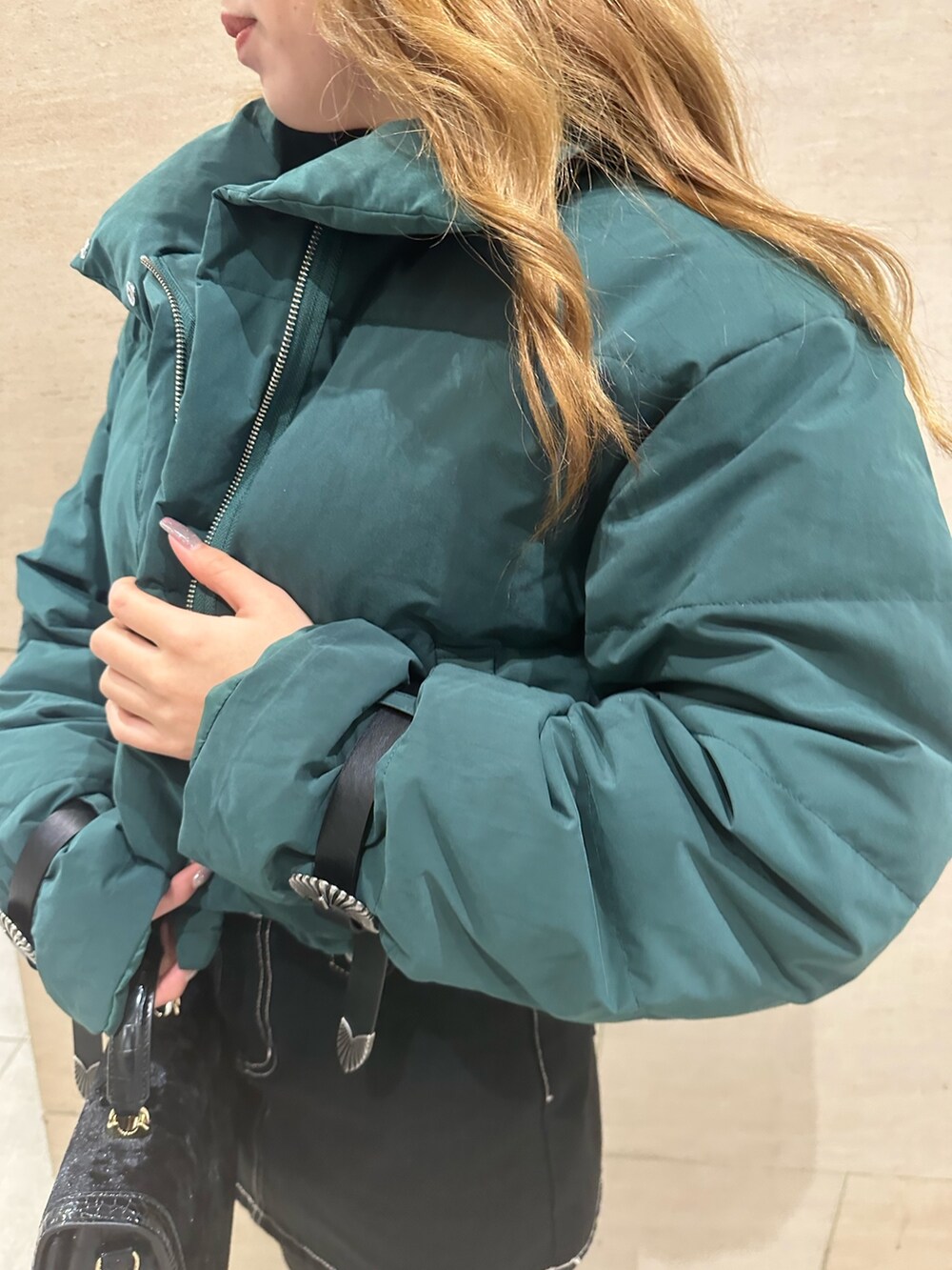 ブルー系のデニムスカート、ホワイト系のTシャツ/カットソー、グリーン系のダウンジャケット/コートを着用したレディースの秋コーディネートの4枚目の写真