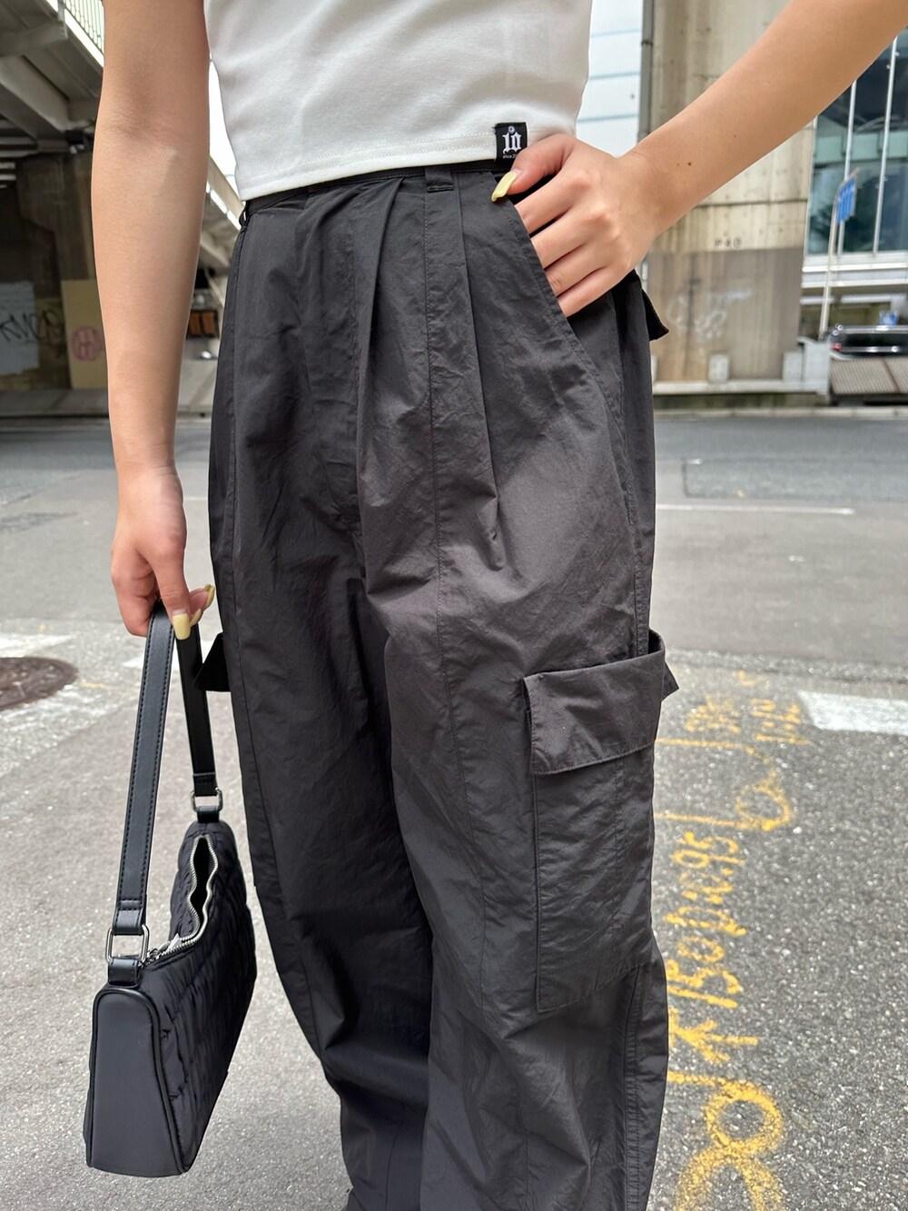 ブラック系のカーゴパンツ、ホワイト系のTシャツ/カットソー、ブラック系のハンドバッグを着用したレディースの夏コーディネートの7枚目の写真