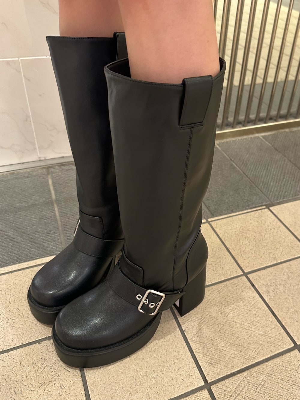 ブルー系のショルダーバッグ、ブラウン系のブーツ、ブラック系のワンピースを着用したレディースの春コーディネートの8枚目の写真