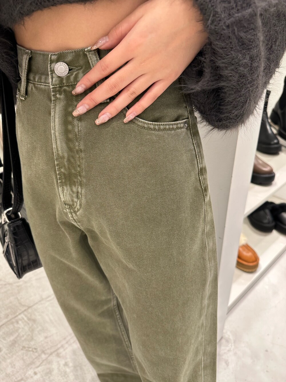 グリーン系のデニムパンツ、グレー系のニット/セーター、ブラック系のショルダーバッグを着用したレディースの冬コーディネートの7枚目の写真