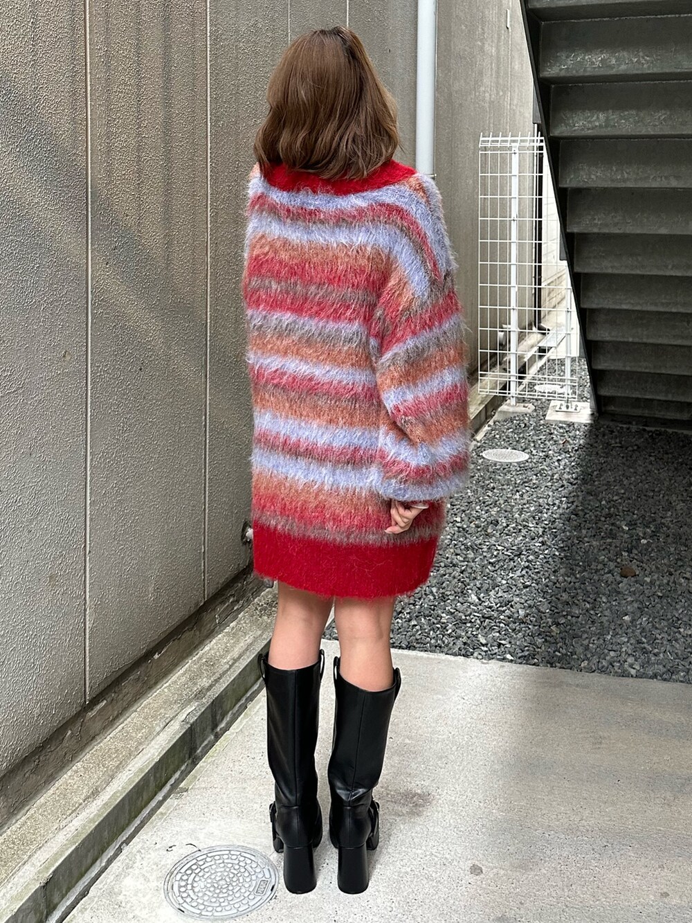 ブラウン系のブーツ、レッド系のカーディガン/ボレロ、ホワイト系のTシャツ/カットソーを着用したレディースの冬コーディネートの3枚目の写真