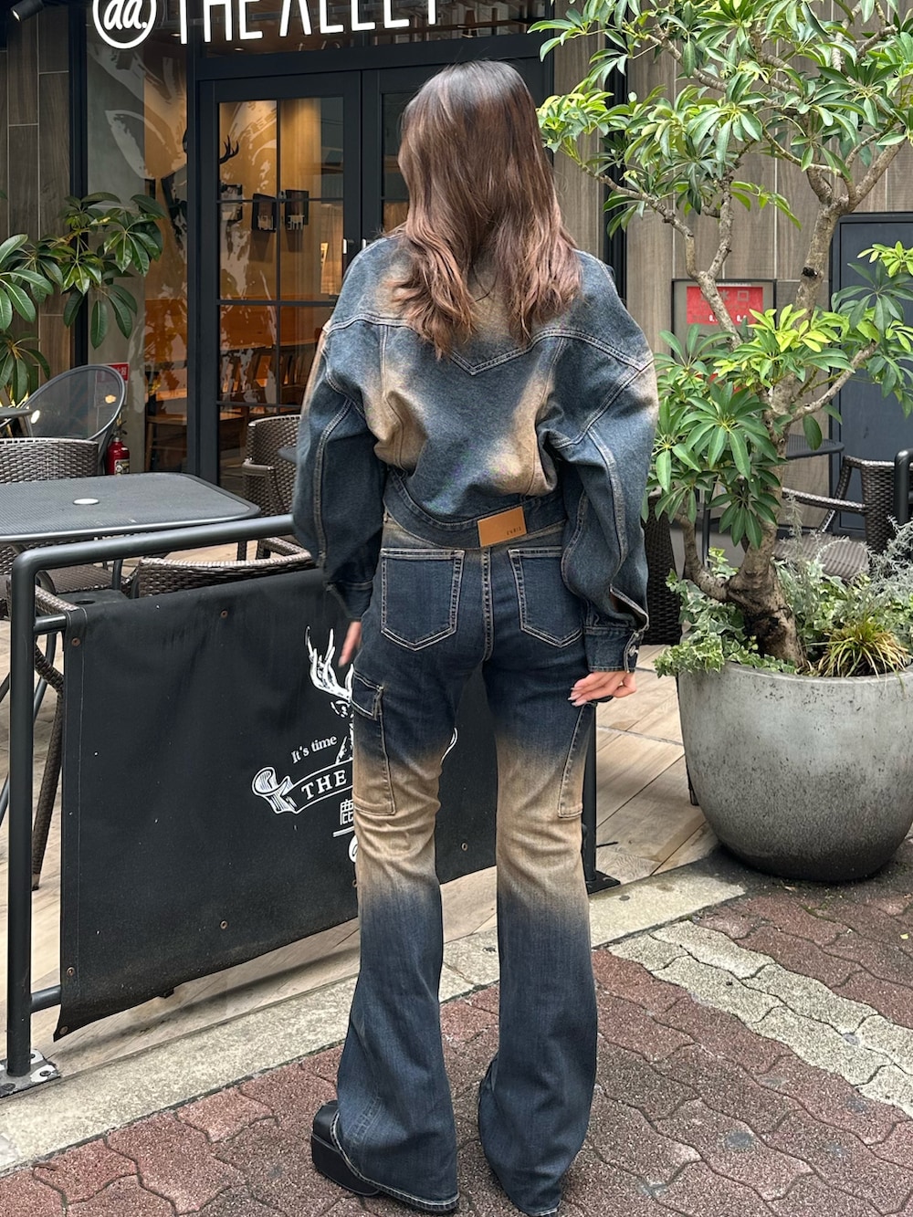 ブルー系のデニムパンツ、ブルー系のデニムジャケット、ブラック系のブーツを着用したレディースの秋コーディネートの3枚目の写真