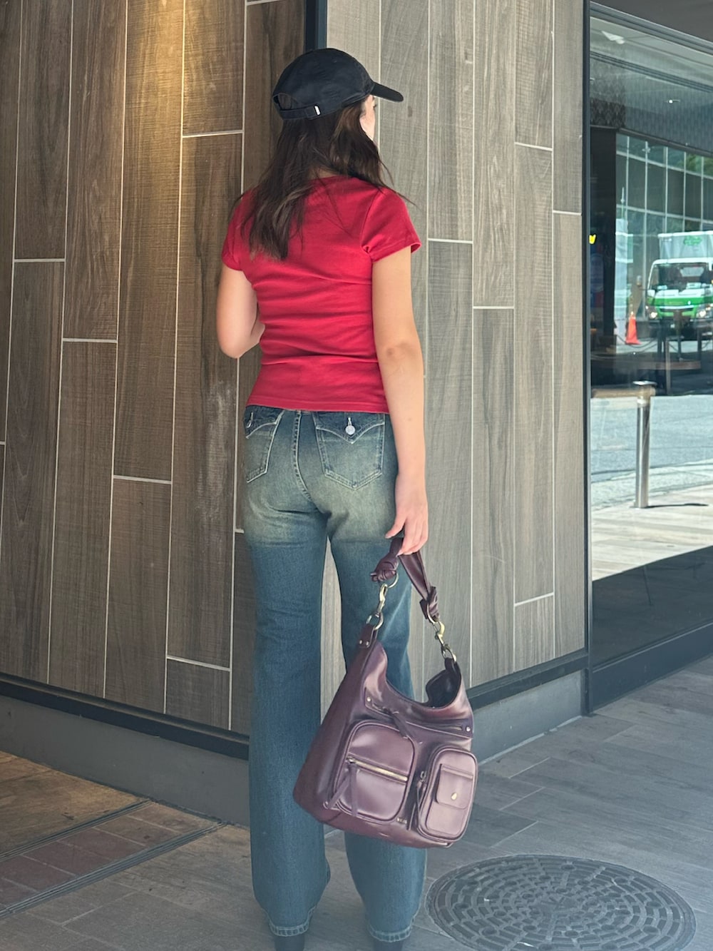 ブルー系のデニムパンツ、レッド系のハンドバッグ、ブラック系のブーツを着用したレディースの秋コーディネートの3枚目の写真