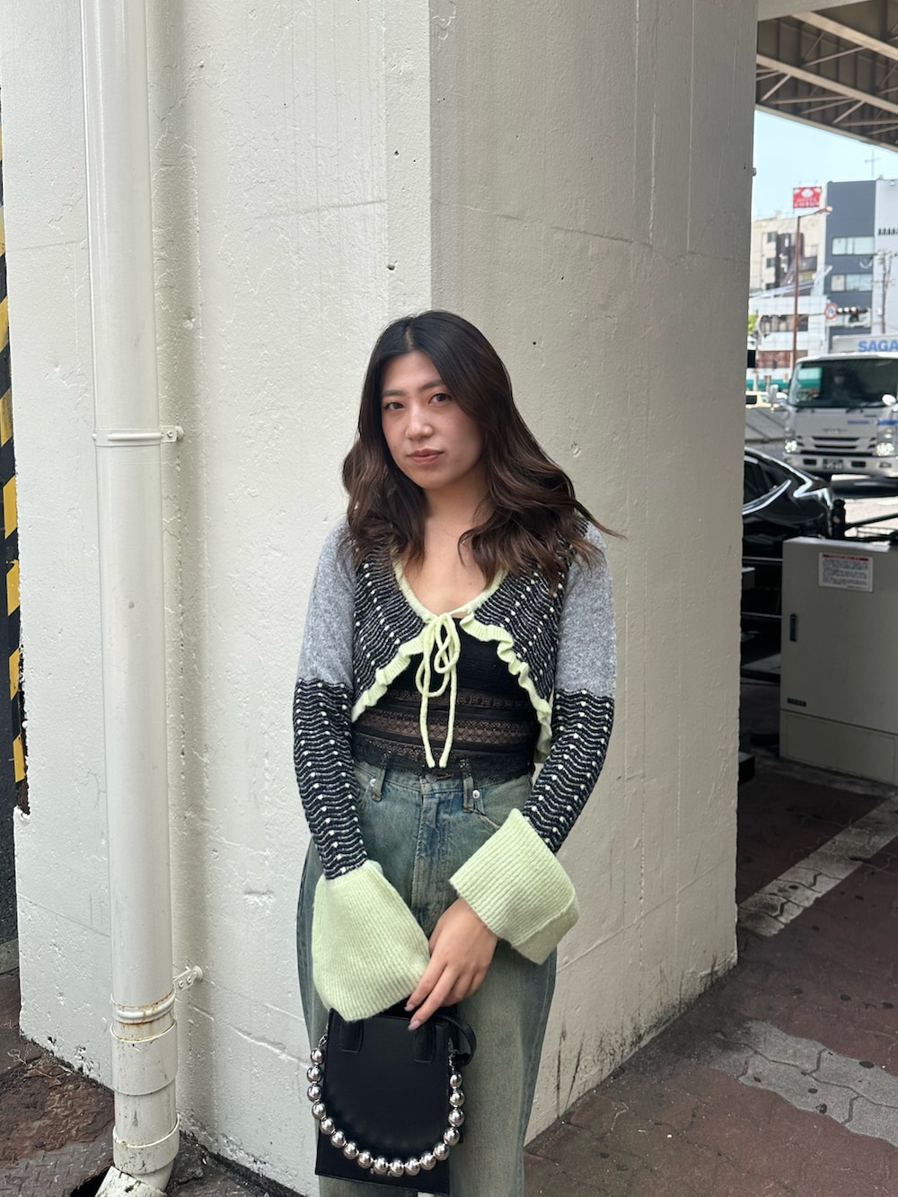 イエロー系のニット/セーター、ブルー系のデニムパンツ、ブラック系のショルダーバッグを着用したレディースの秋コーディネートの4枚目の写真