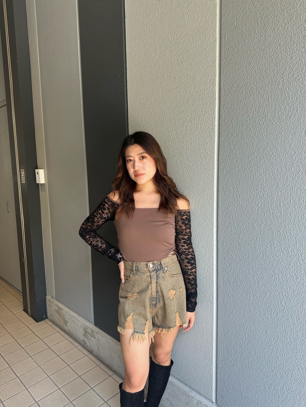 ブルー系のデニムパンツ、ブラック系のブーツ、ブラウン系のTシャツ/カットソーを着用したレディースの秋コーディネートの4枚目の写真