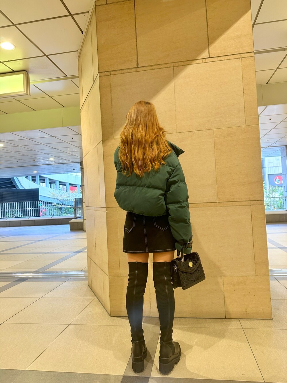 ブルー系のデニムスカート、ホワイト系のTシャツ/カットソー、グリーン系のダウンジャケット/コートを着用したレディースの秋コーディネートの2枚目の写真