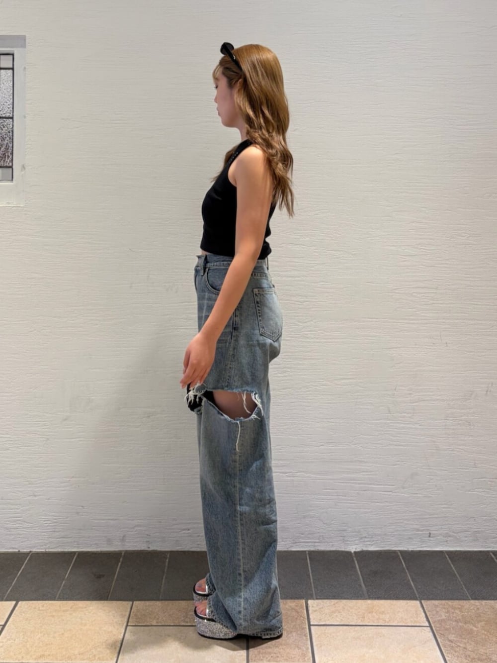 ブルー系のデニムパンツ、ブラック系のショルダーバッグ、シルバー系のサンダルを着用したレディースの夏コーディネートの2枚目の写真