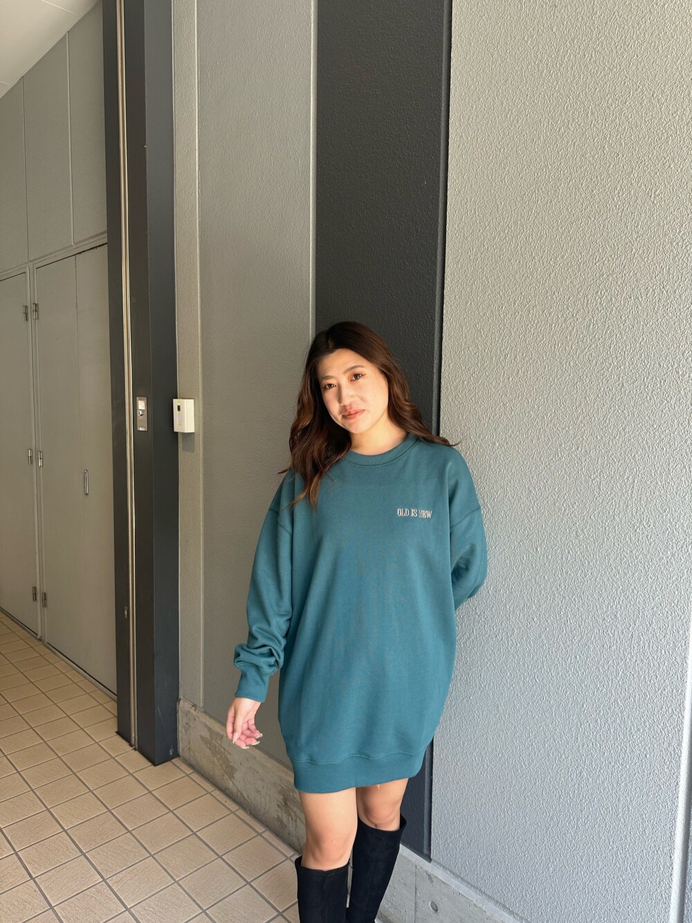 ブルー系のスウェット、ブラック系のブーツ、ブルー系のデニムパンツを着用したレディースの秋コーディネートの4枚目の写真