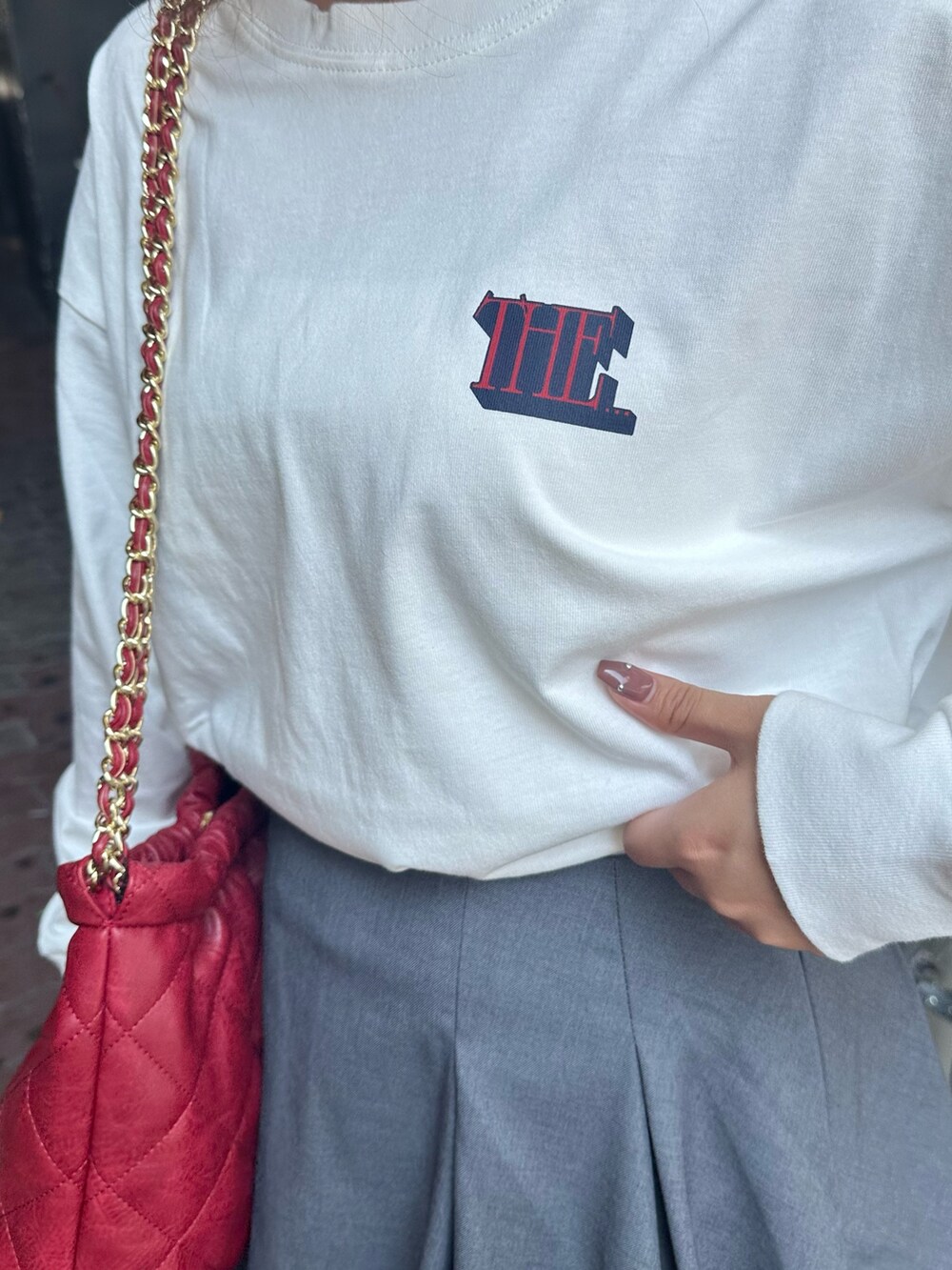 ホワイト系のTシャツ/カットソー、グレー系のスカート、ブラック系のブーツを着用したレディースの秋コーディネートの6枚目の写真