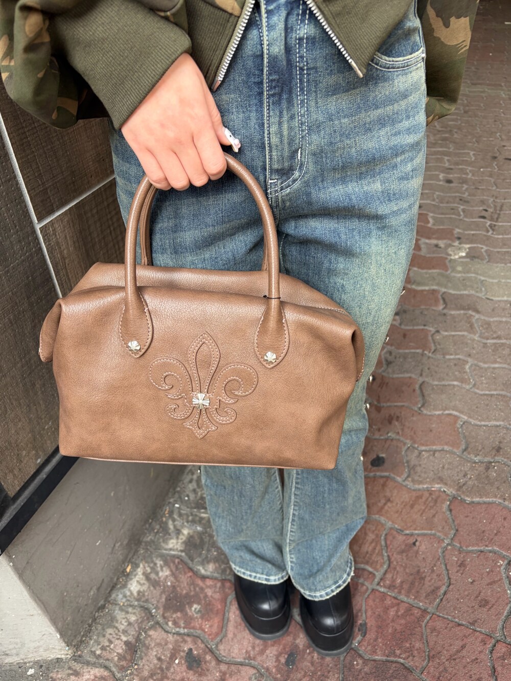 ブルー系のデニムパンツ、ブラウン系のボストンバッグ、ブラック系のブーツを着用したレディースの冬コーディネートの7枚目の写真