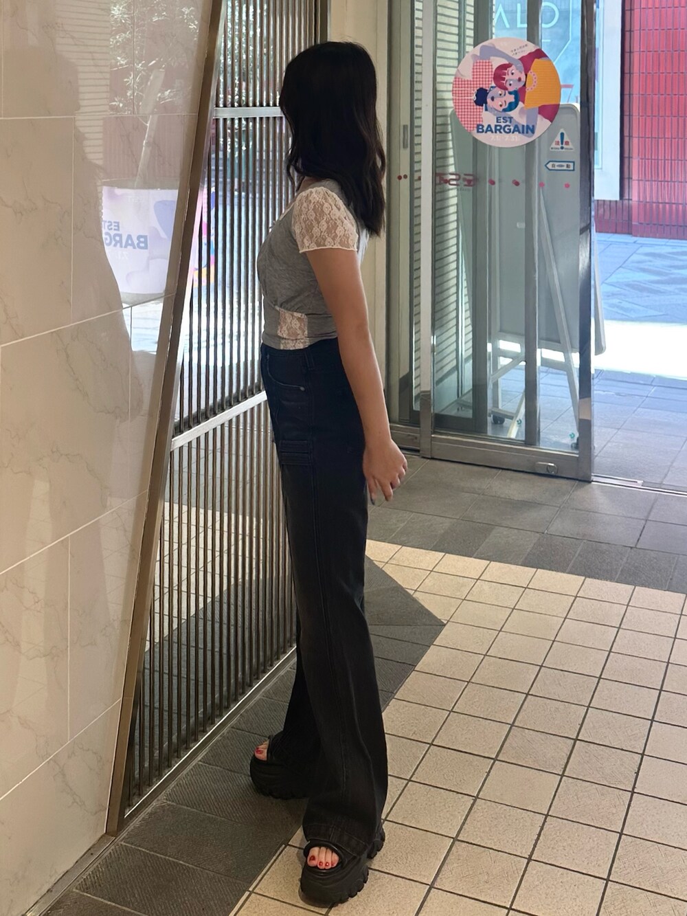 ブラック系のデニムパンツ、ブラック系のサンダル、グレー系のTシャツ/カットソーを着用したレディースの夏コーディネートの2枚目の写真