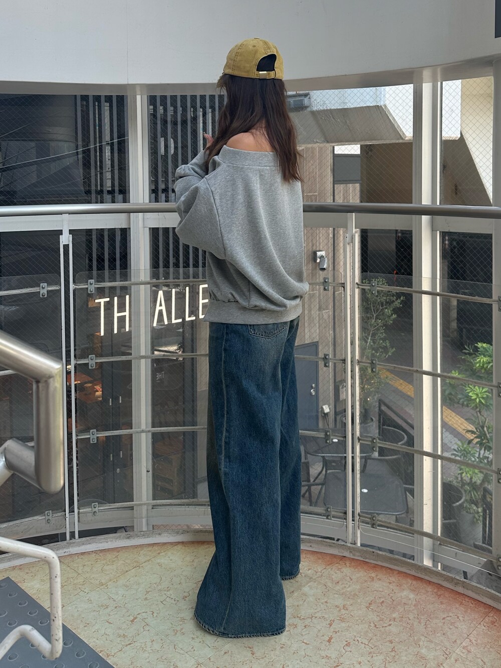 ブルー系のデニムパンツ、グレー系のパーカー、ブラック系のハンドバッグを着用したレディースの秋コーディネートの3枚目の写真