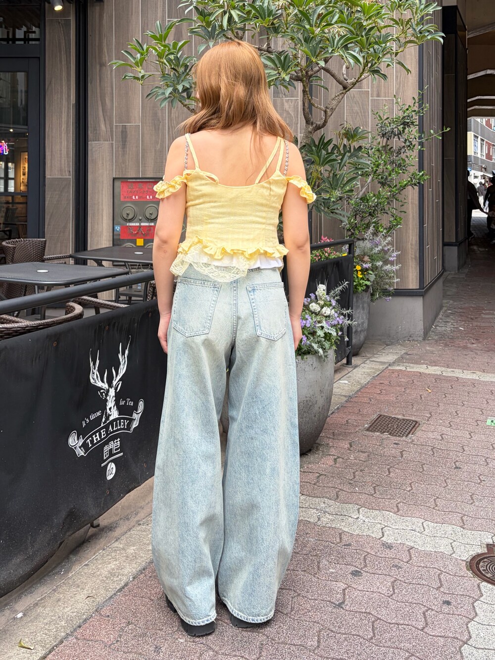 ブルー系のデニムパンツ、イエロー系のキャミソールを着用したレディースの春コーディネートの3枚目の写真
