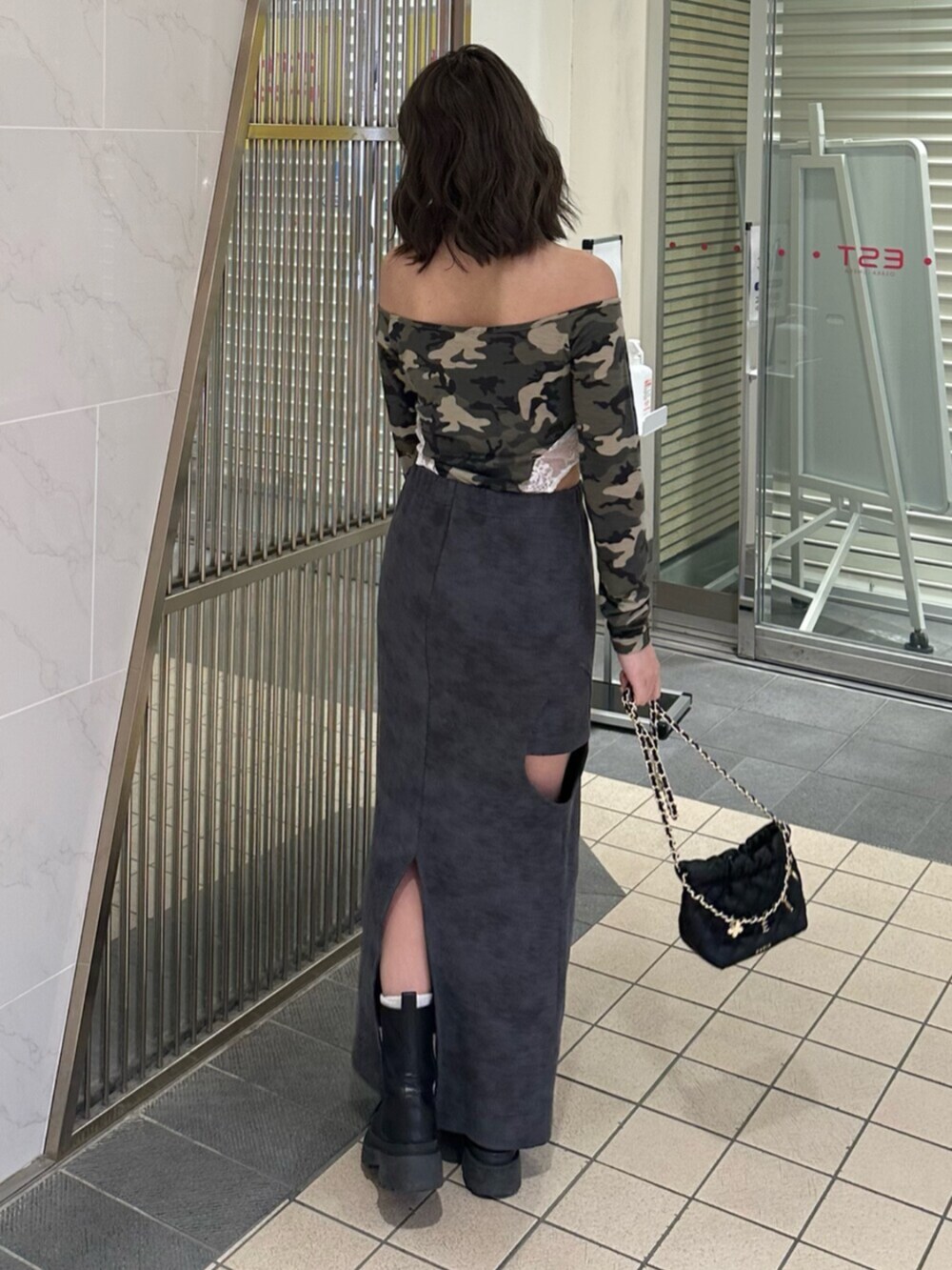 ブラック系のブーツ、ブラック系のスカート、ブラック系のショルダーバッグを着用したレディースの冬コーディネートの3枚目の写真