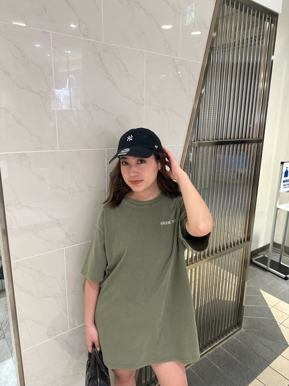 ブラック系のショルダーバッグ、ブラウン系のブーツ、グリーン系のTシャツ/カットソーを着用したレディースの春コーディネートの4枚目の写真