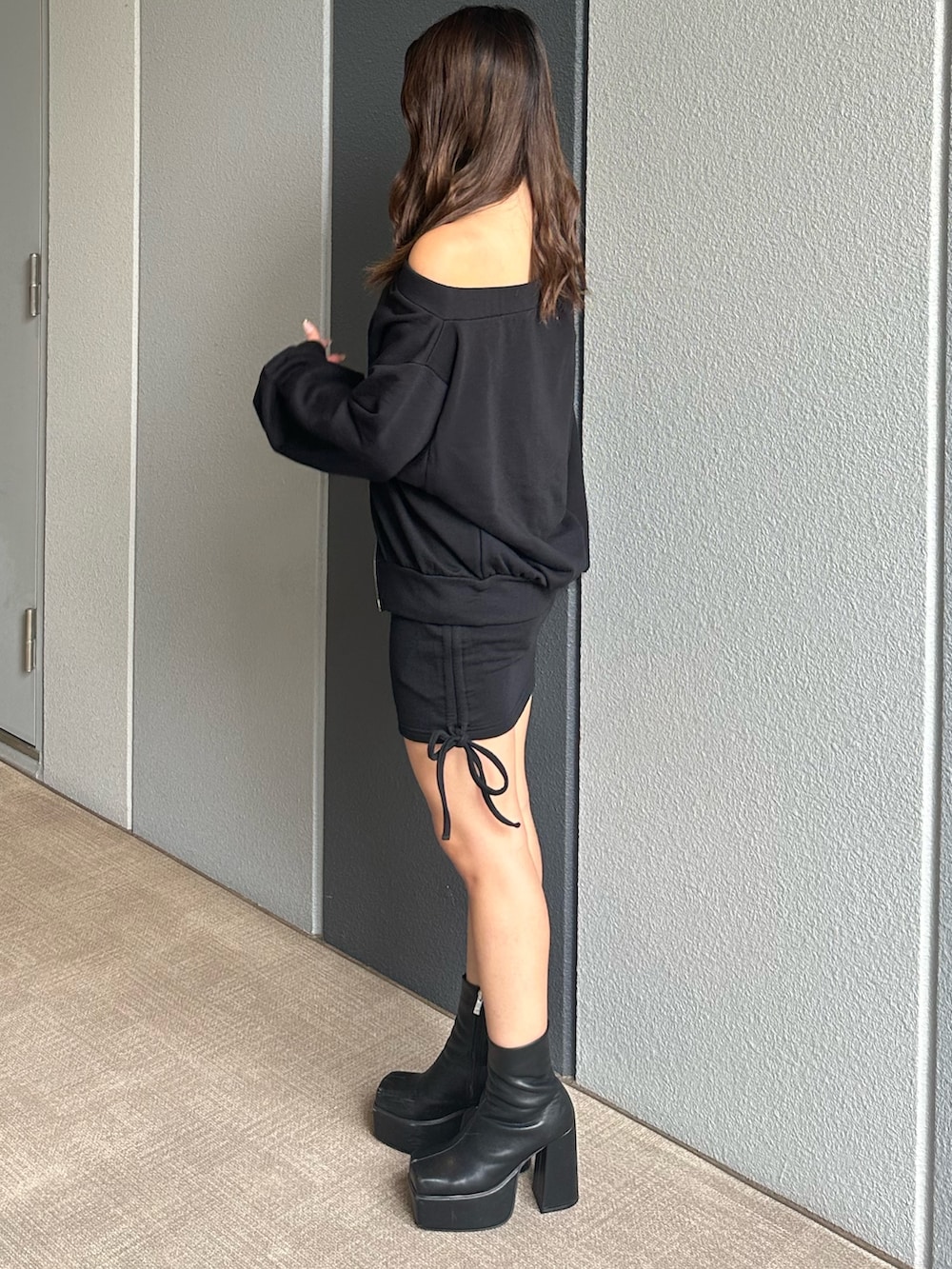 ブラック系のパーカー、ブラック系のスカート、ブラック系のブーツを着用したレディースの秋コーディネートの2枚目の写真