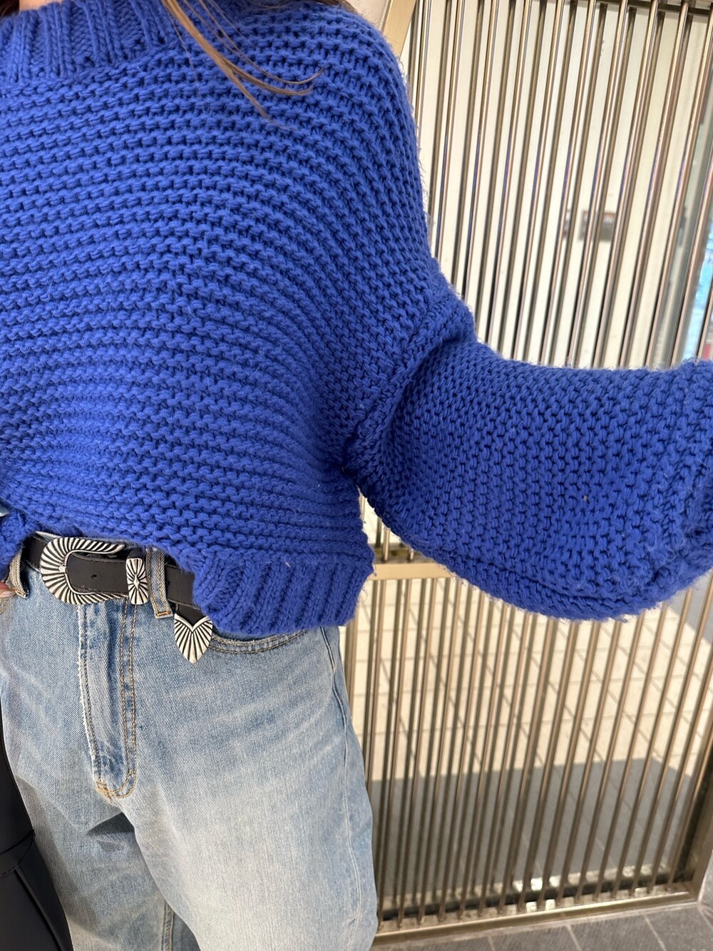 ブラック系のハンドバッグ、ブルー系のニット/セーター、ブルー系のデニムパンツを着用したレディースの冬コーディネートの4枚目の写真