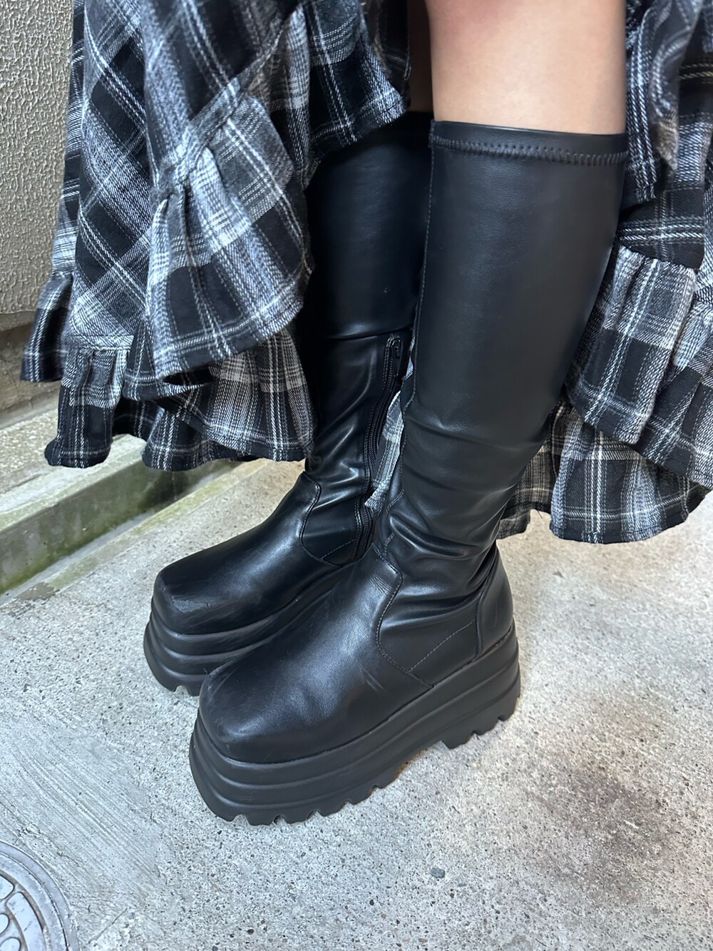 グレー系のニット/セーター、ブラック系のスカート、ブラック系のブーツを着用したレディースの冬コーディネートの9枚目の写真