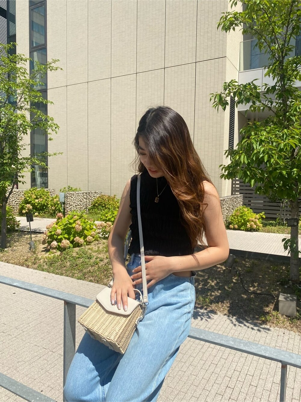 ブルー系のデニムパンツ、ブラック系のサンダル、ホワイト系のショルダーバッグを着用したレディースの夏コーディネートの4枚目の写真