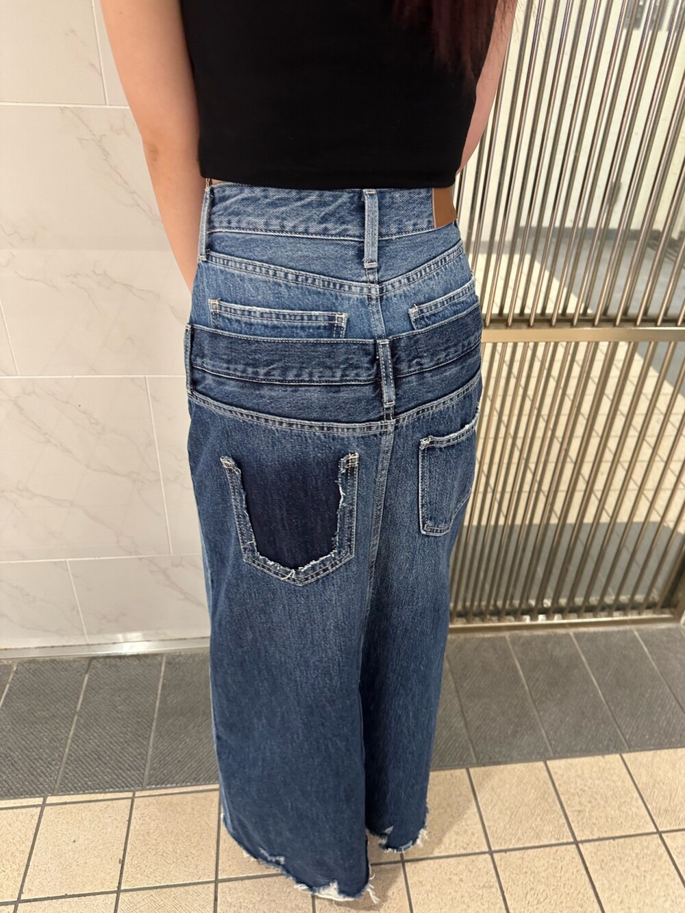 ブルー系のデニムスカート、ブラック系のタンクトップ、ブラック系のサンダルを着用したレディースの春コーディネートの8枚目の写真