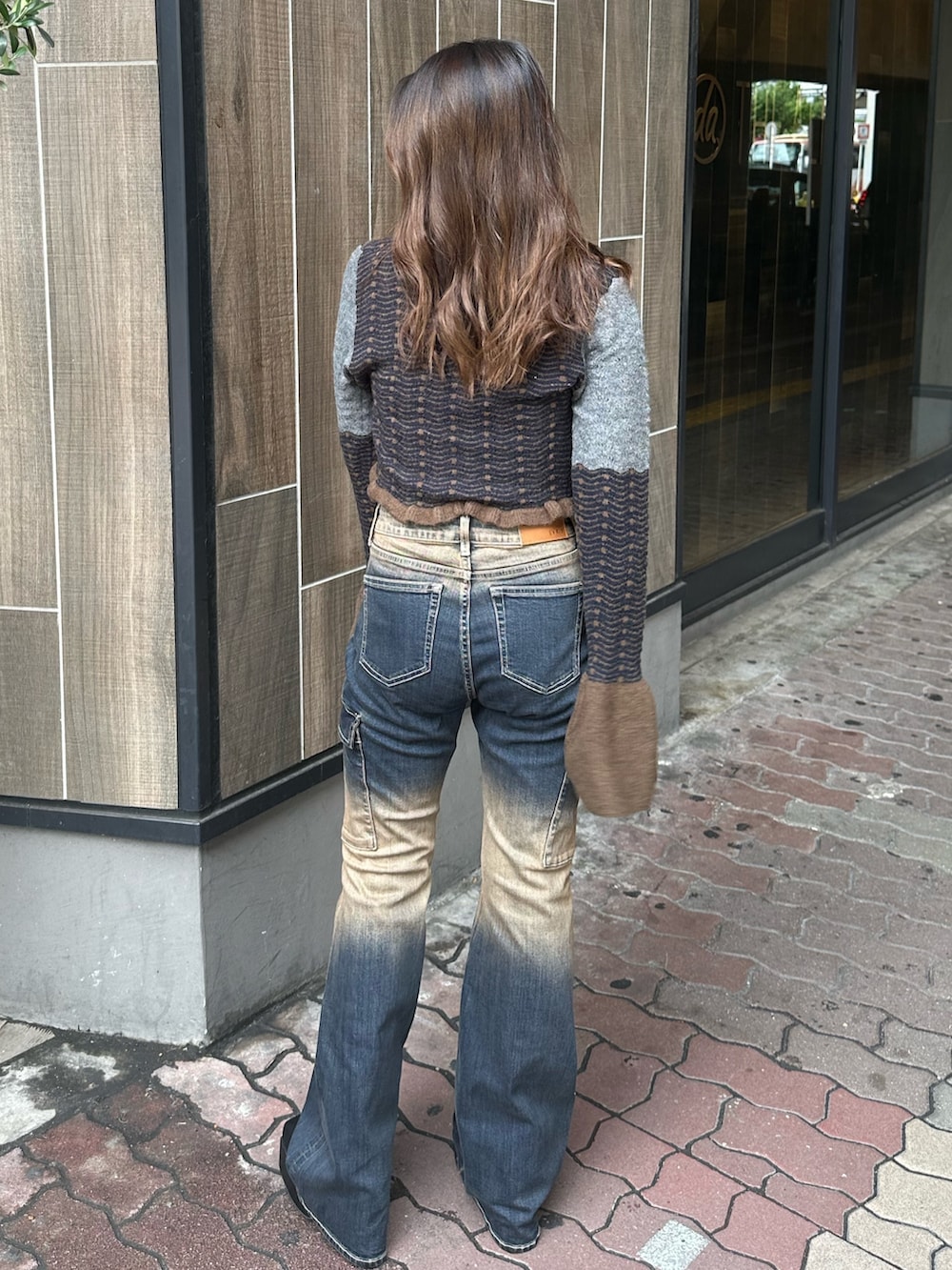 ブルー系のデニムパンツ、ブラック系のブーツ、ブラウン系のニット/セーターを着用したレディースの秋コーディネートの3枚目の写真
