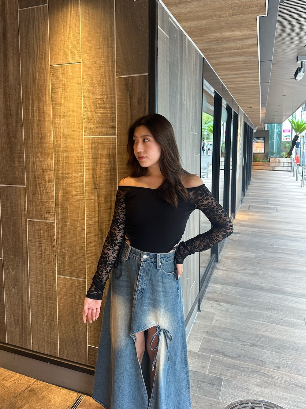 ブルー系のデニムスカート、ブラック系のTシャツ/カットソー、ブラック系のブーツを着用したレディースの秋コーディネートの4枚目の写真