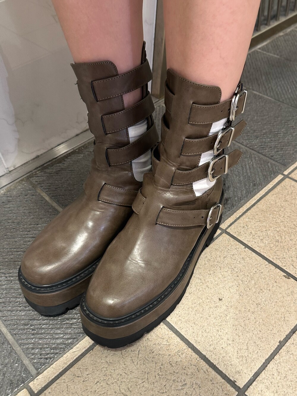 ブラック系のショルダーバッグ、ブラウン系のブーツ、グリーン系のTシャツ/カットソーを着用したレディースの春コーディネートの7枚目の写真