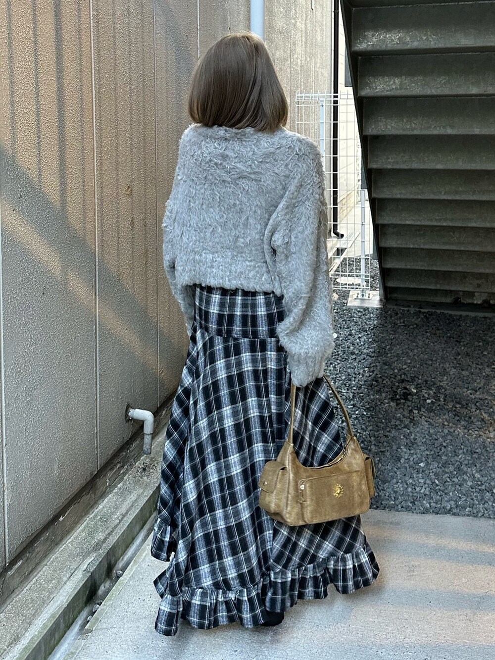 グレー系のニット/セーター、ブラック系のスカート、ブラック系のブーツを着用したレディースの冬コーディネートの4枚目の写真