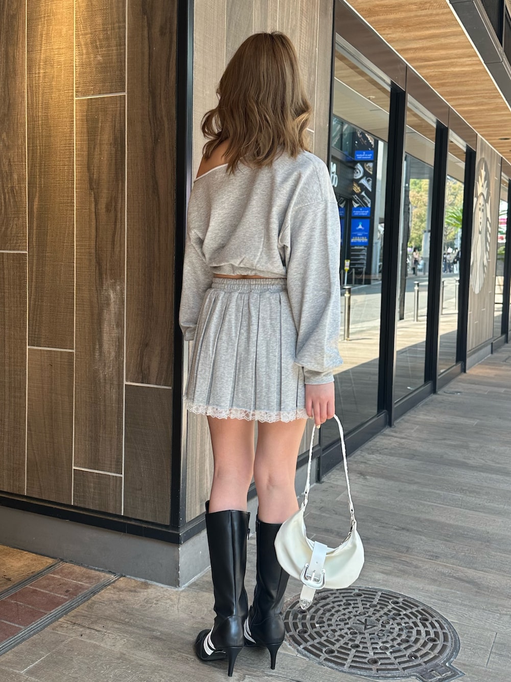 ホワイト系のショルダーバッグ、ブラック系のブーツ、グレー系のスウェットを着用したレディースの春コーディネートの3枚目の写真